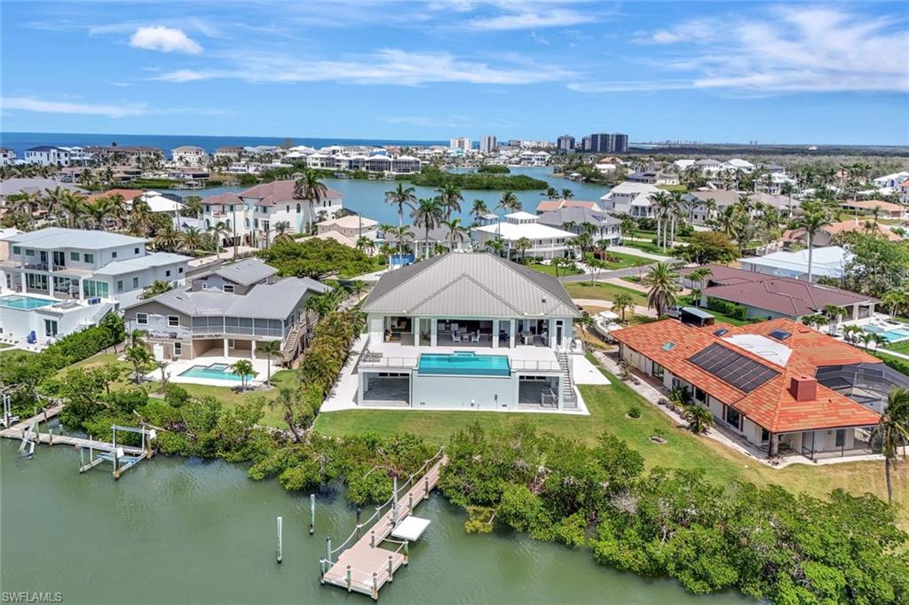 Aerial view of residential area featuring a nearby body of water and a pool