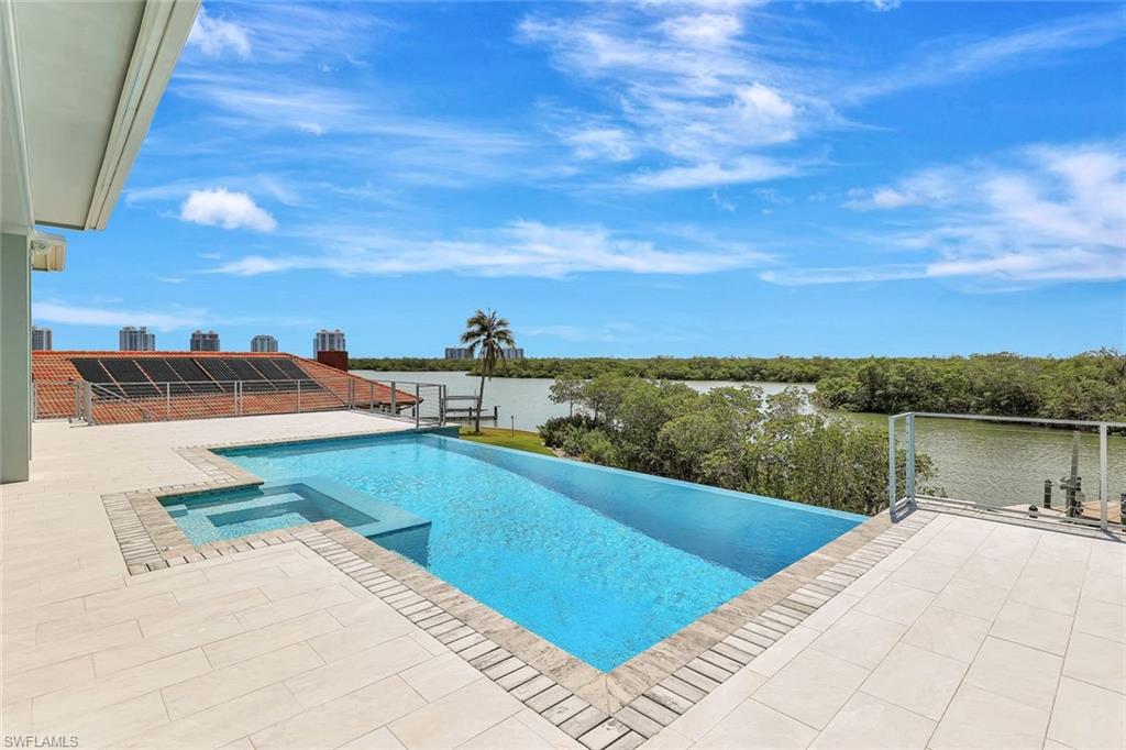 View of swimming pool featuring a pool with connected hot tub, a patio area, and a water view