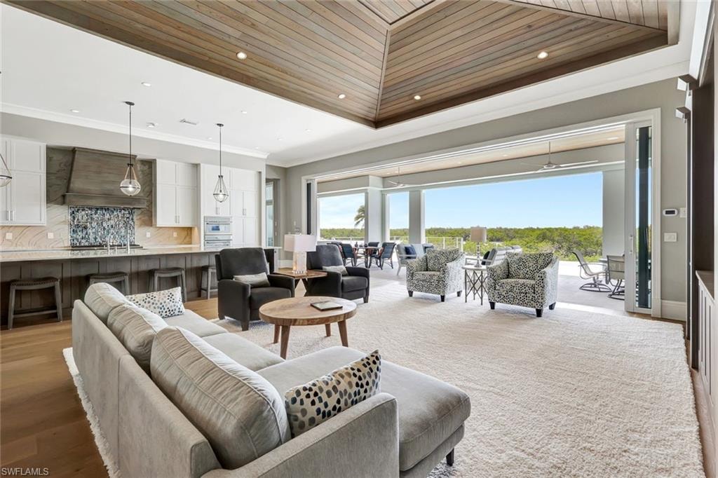 Living room with wooden ceiling, crown molding, a tray ceiling, recessed lighting, and light wood finished floors