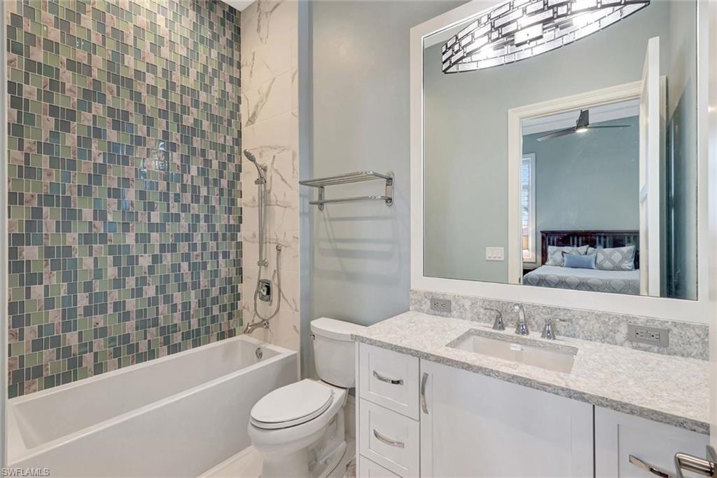 Guest 1 Ensuite bathroom featuring toilet, vanity, bathtub / shower combination, and a ceiling fan