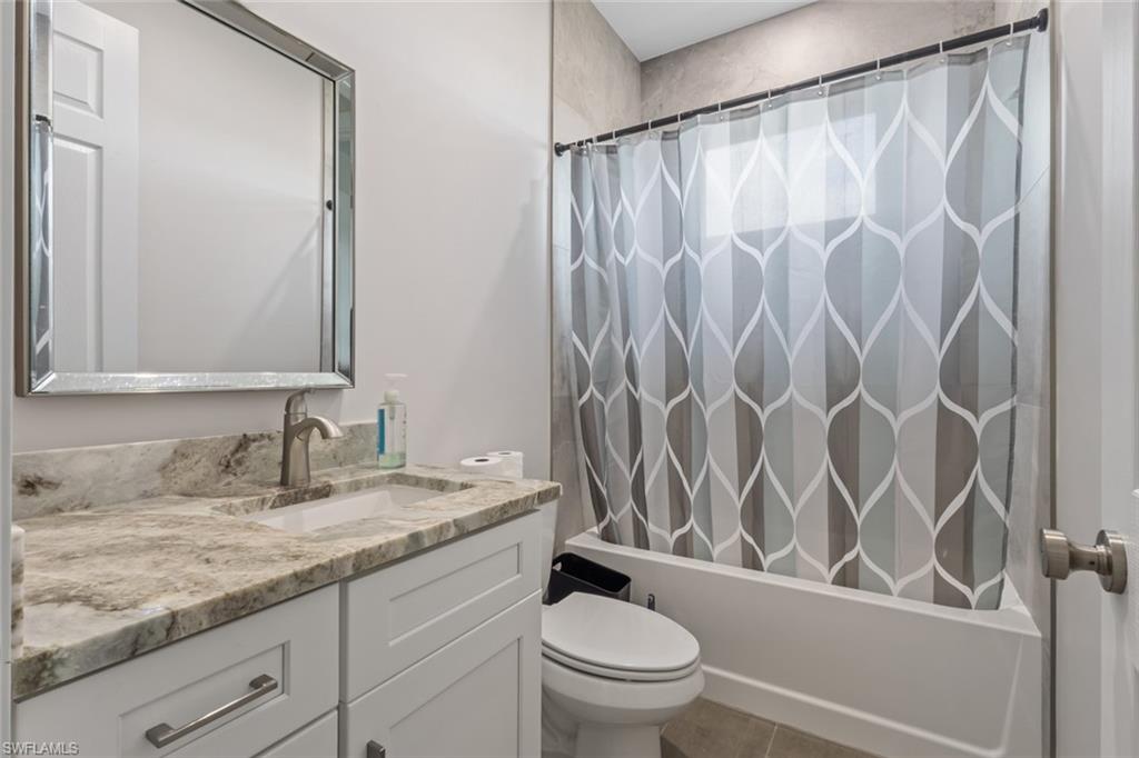 Bathroom featuring vanity, shower / bathtub combination with curtain, and tile patterned flooring