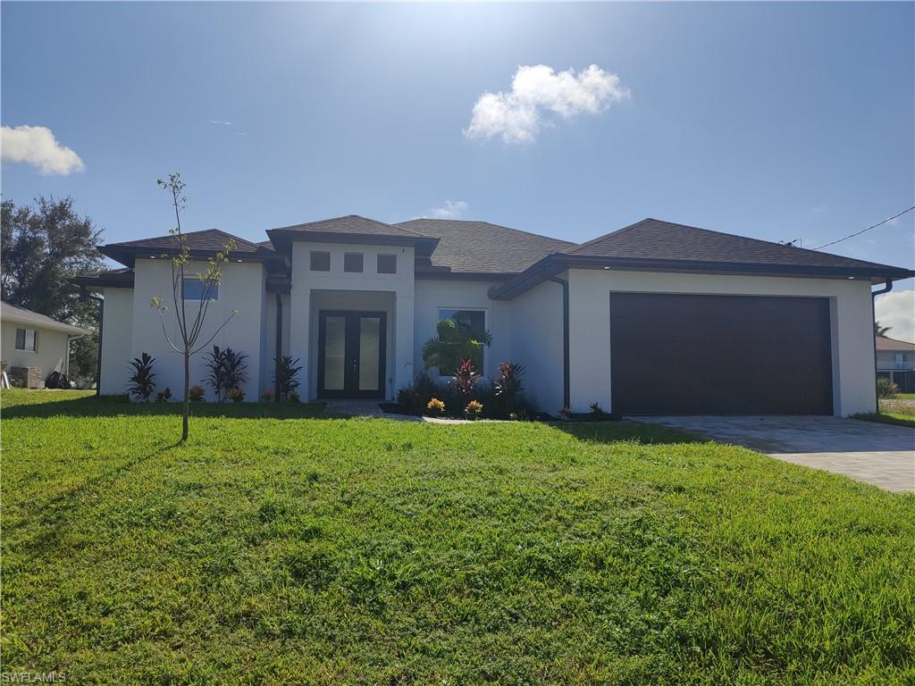 Prairie-style house featuring french doors, stucco siding, a front lawn, and a garage