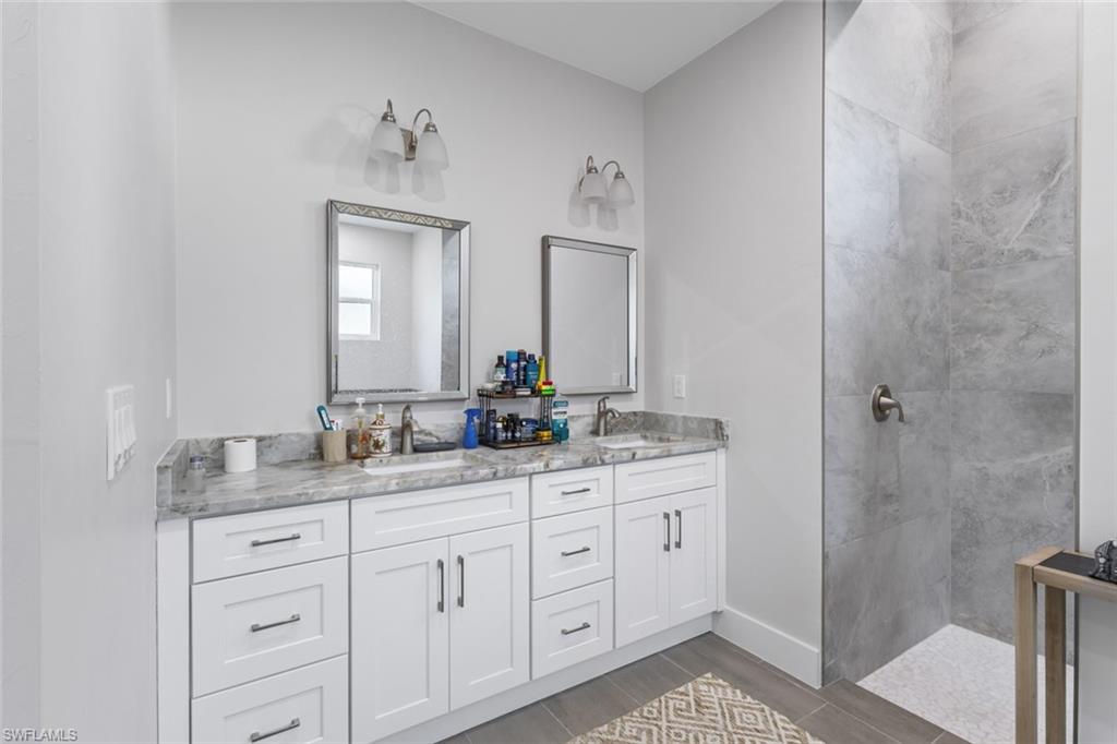 Full bath featuring double vanity, walk in shower, and wood finished floors