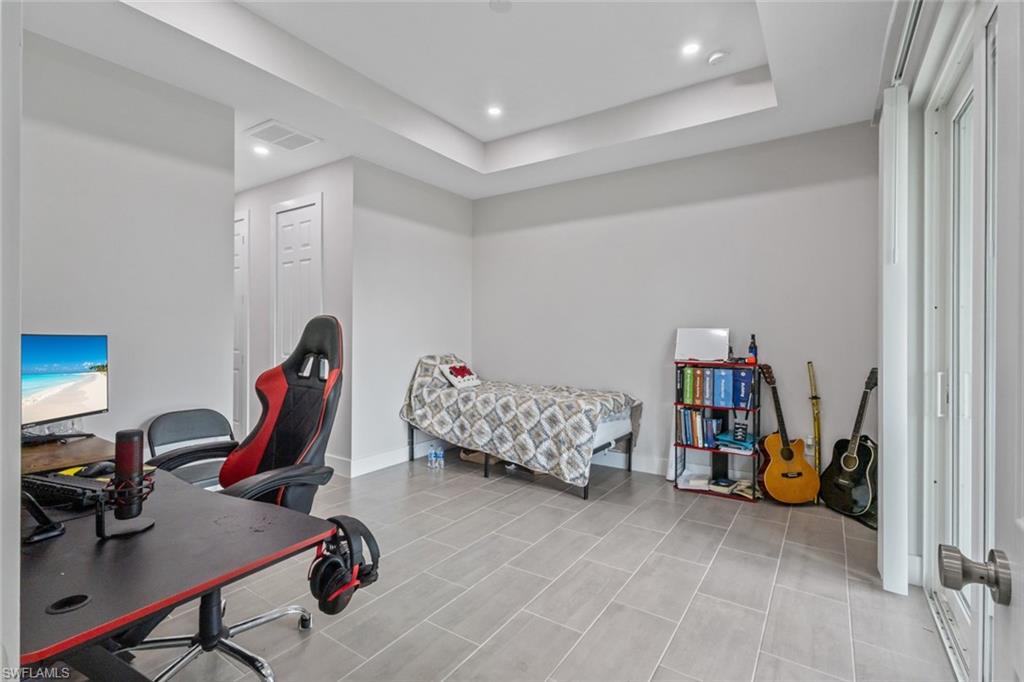 Bedroom with a desk, a raised ceiling, and recessed lighting