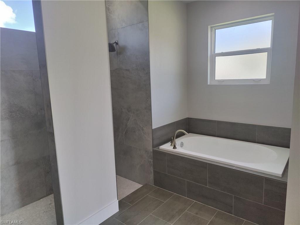 Bathroom featuring walk in shower, a garden tub, healthy amount of natural light, and tile patterned flooring