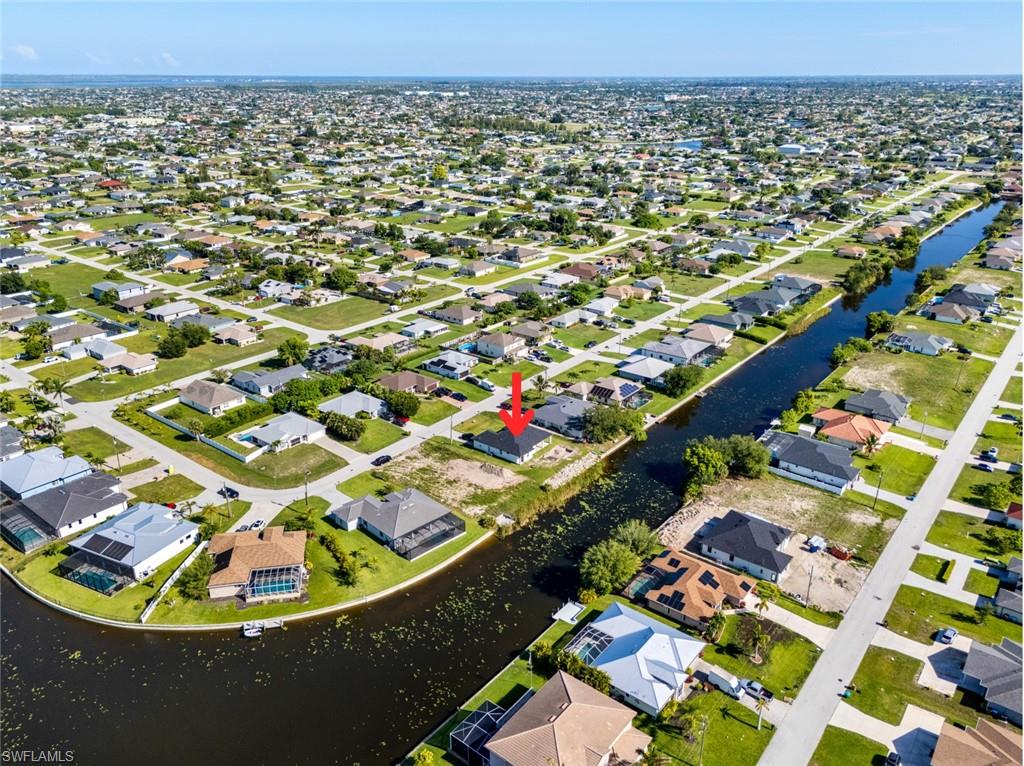 Aerial view of property and surrounding area featuring a nearby body of water and nearby suburban area