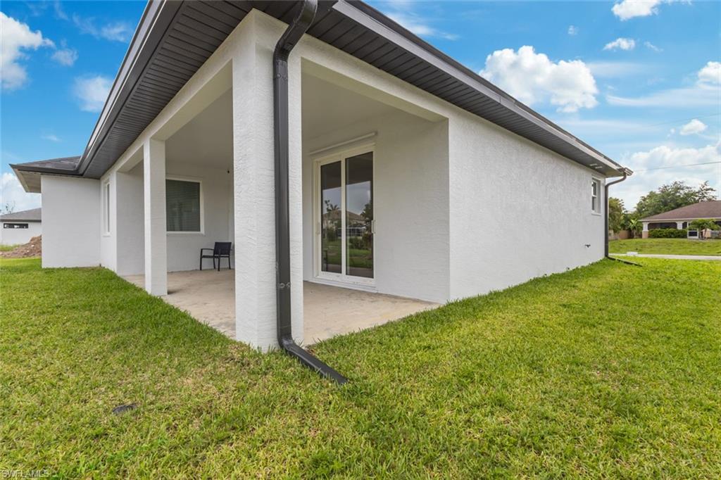 Rear view of house with stucco siding, a patio area, and a yard
