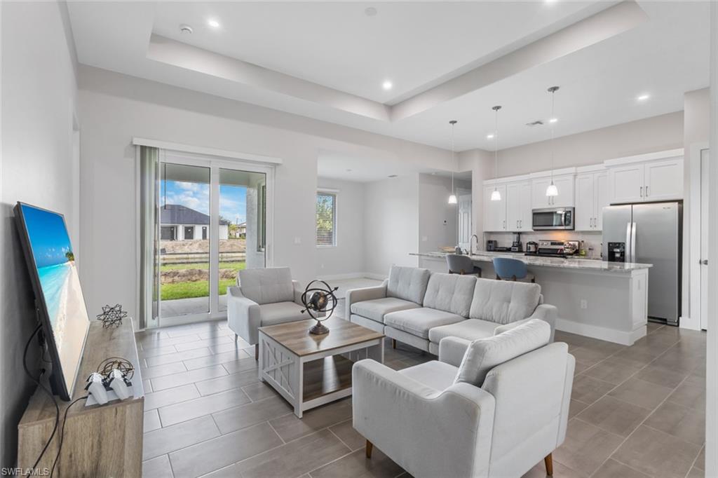 Living area with a tray ceiling, recessed lighting, and tile patterned flooring