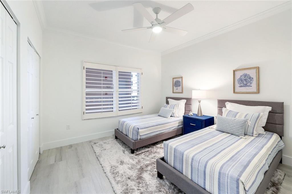 Bedroom featuring wood finished floors, crown molding, baseboards, a closet, and ceiling fan