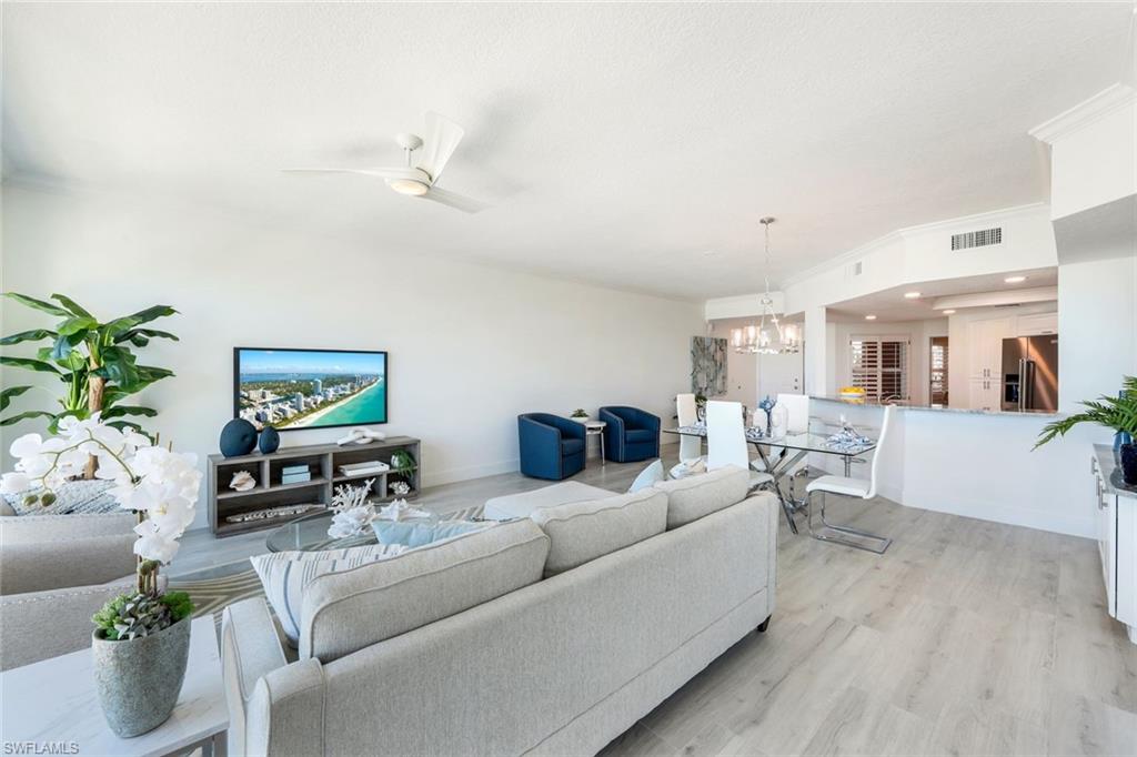 Living room featuring a chandelier, light wood-style floors, baseboards, and ceiling fan