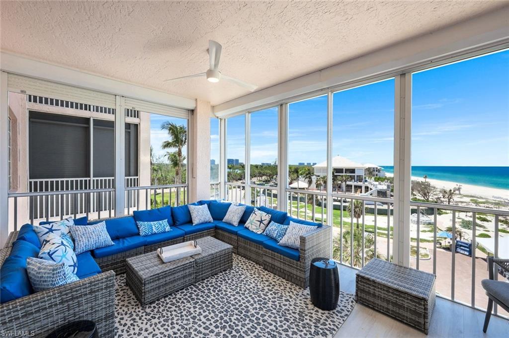 Sunroom featuring an outdoor living space, view of water and beach, ceiling fan, a textured ceiling, and wood finished floors