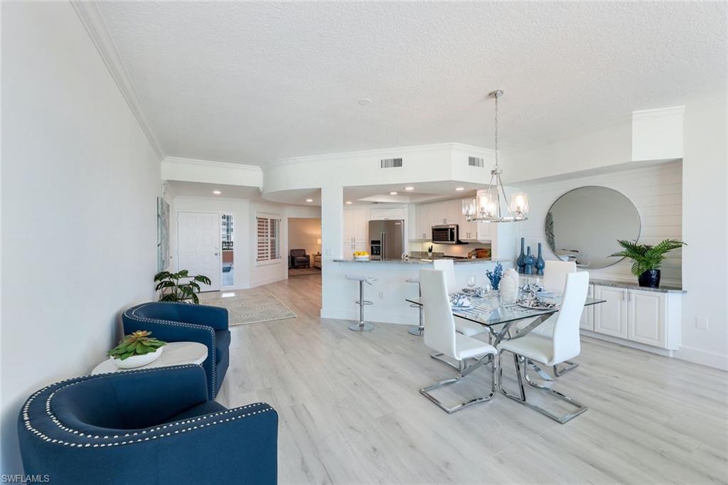 Dining area featuring ornamental molding, a chandelier, light wood-type flooring, a textured ceiling, and baseboards