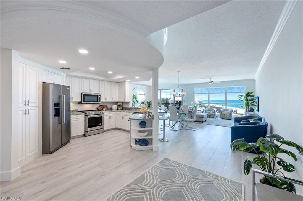 Kitchen featuring stainless steel appliances, open floor plan, white cabinetry, light wood finished floors, and recessed lighting