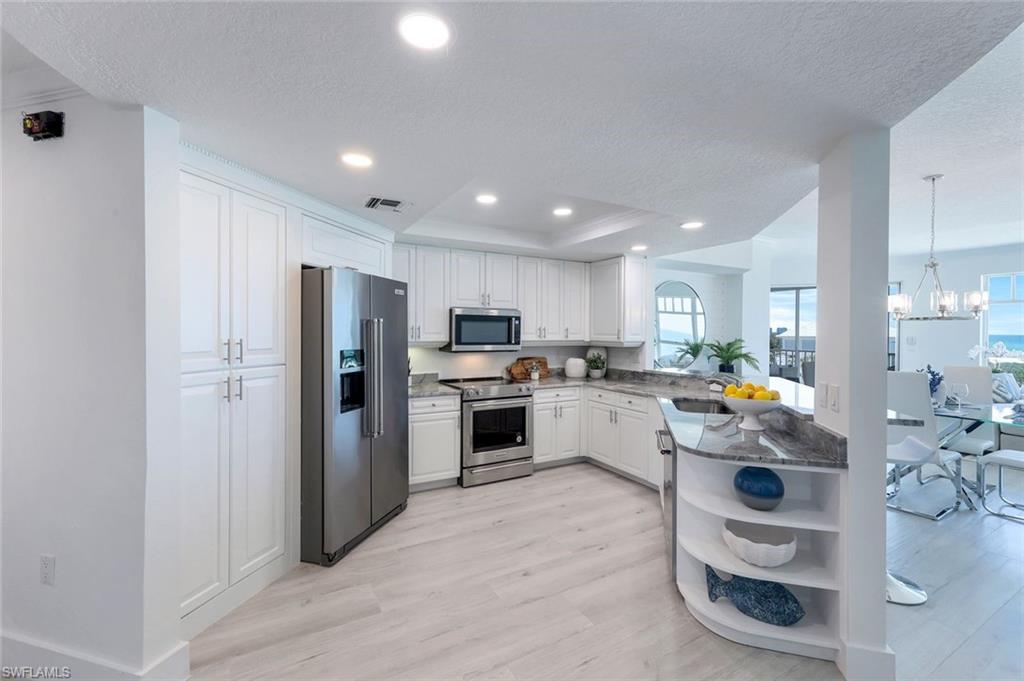 Kitchen featuring appliances with stainless steel finishes, open shelves, light wood-style flooring, a textured ceiling, and white cabinetry