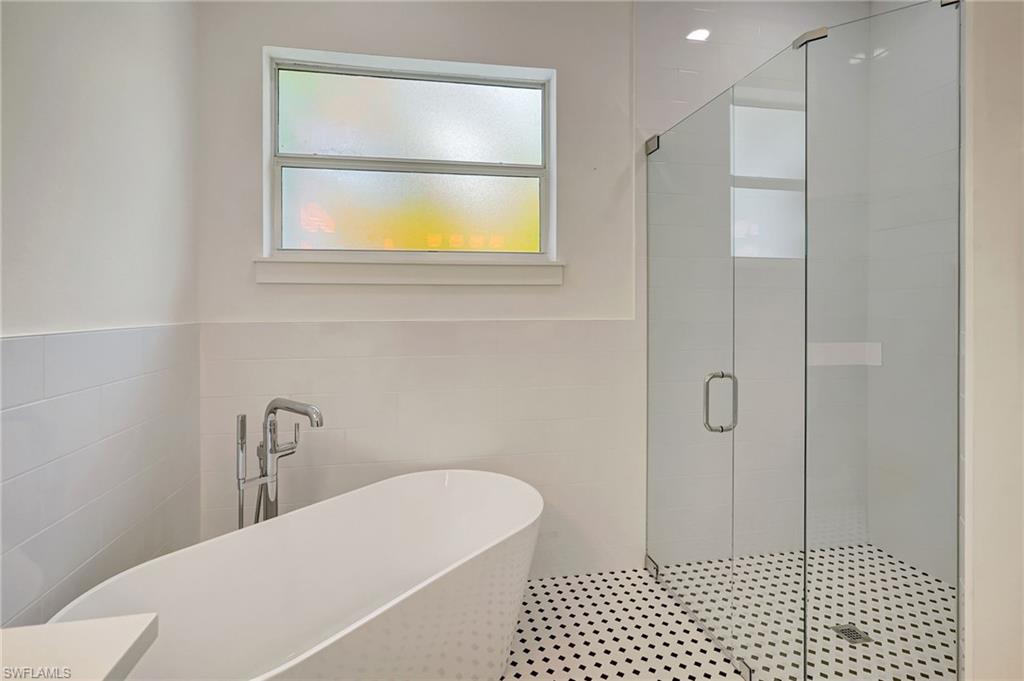 Full bath featuring tile walls, a shower stall, and a freestanding tub