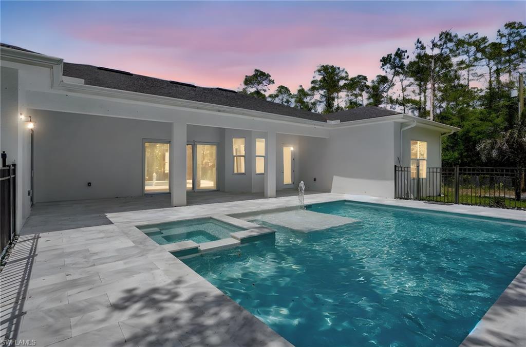View of swimming pool with a patio, a pool with connected hot tub, and fence