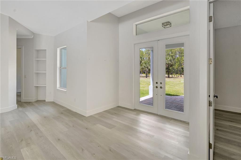 Doorway with french doors, light wood-style floors, baseboards, and built in shelves