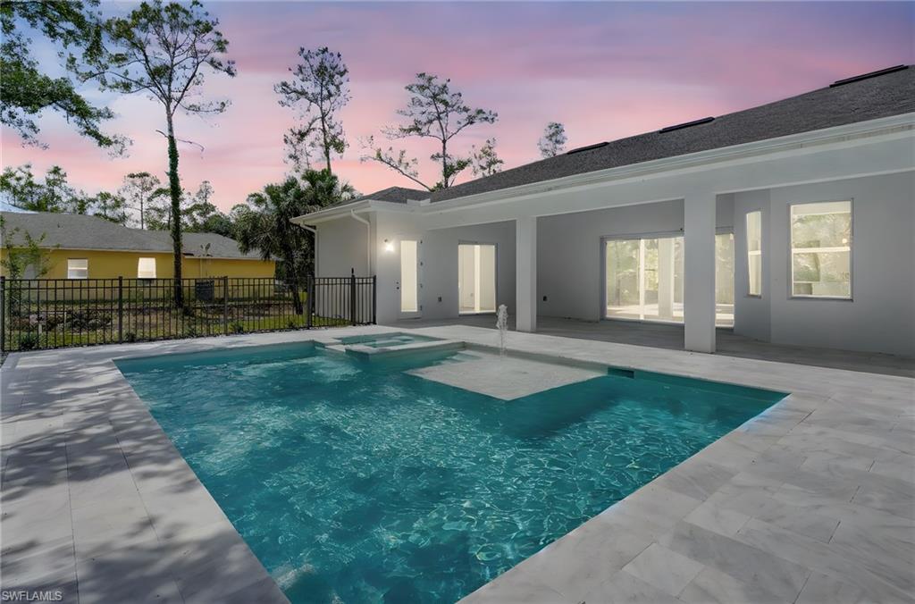 View of swimming pool with a patio, fence, and a pool with connected hot tub