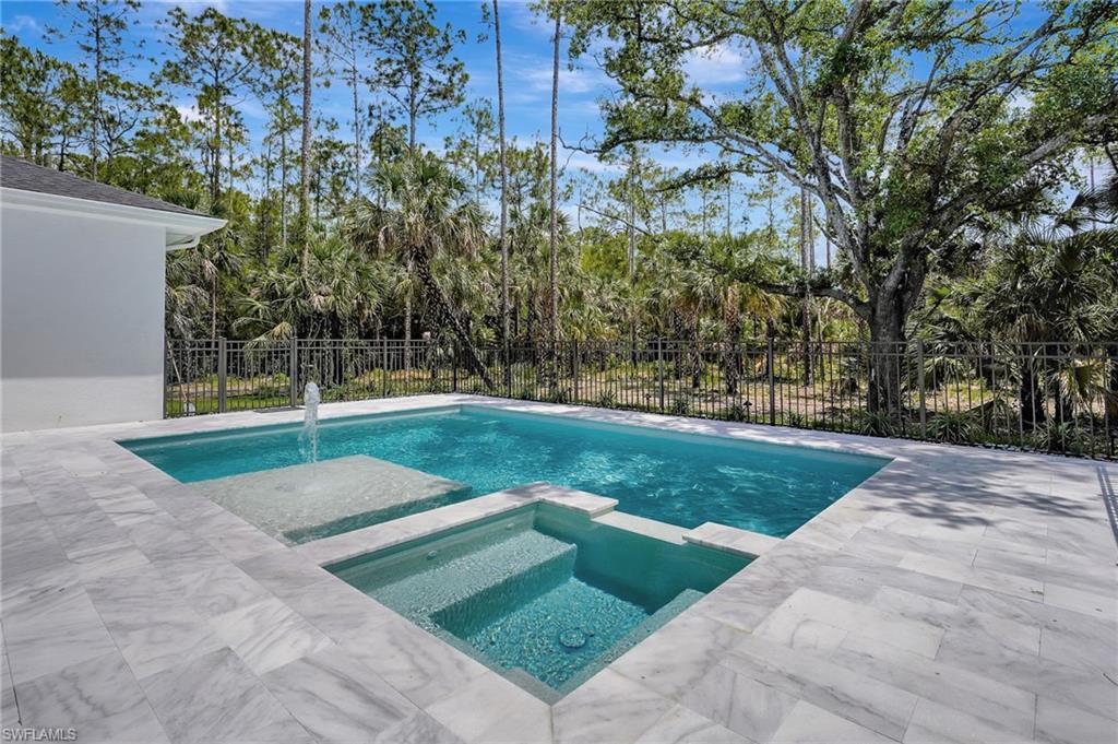 View of pool with fence, a pool with connected hot tub, and a patio