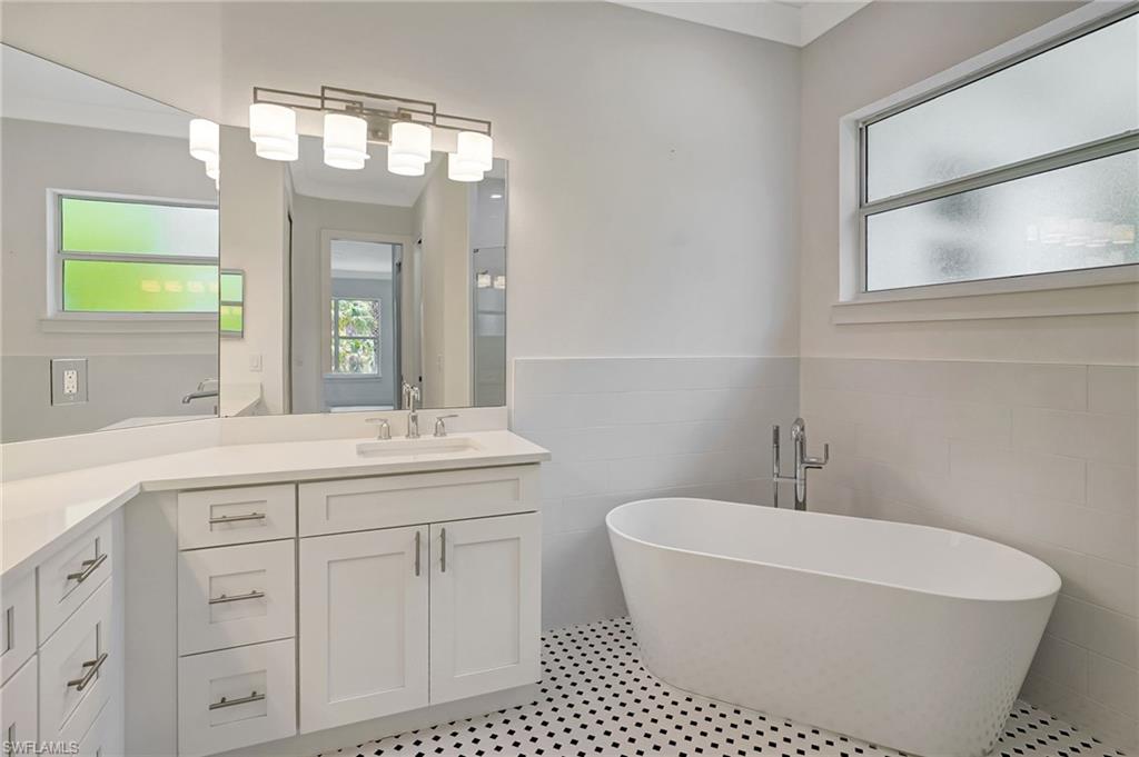 Bathroom featuring tile walls, vanity, a soaking tub, and a wainscoted wall