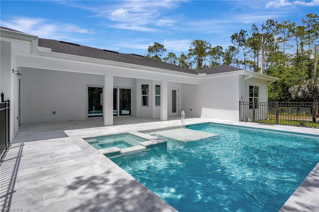 View of pool featuring a patio area, a pool with connected hot tub, and fence