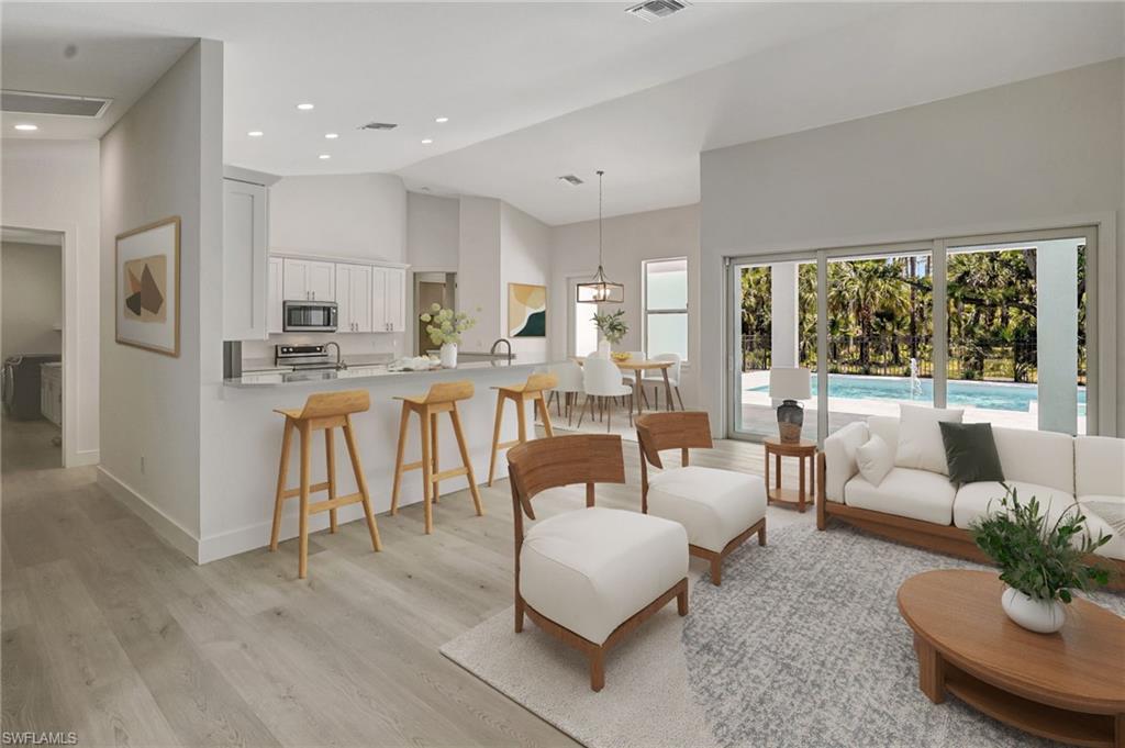 Living area featuring light wood-style floors, baseboards, high vaulted ceiling, and recessed lighting