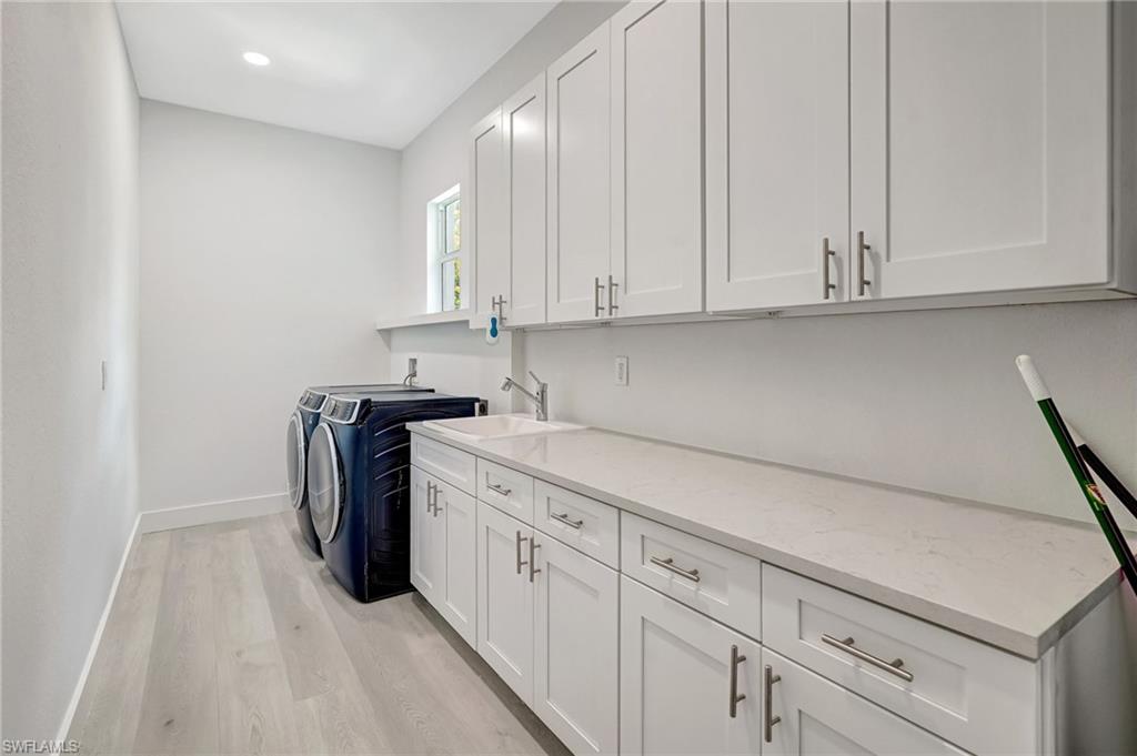 Laundry room with cabinet space, independent washer and dryer, light wood-style floors, baseboards, and recessed lighting