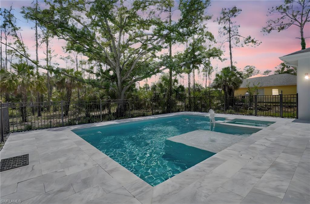 View of swimming pool with a patio, fence, and a pool with connected hot tub