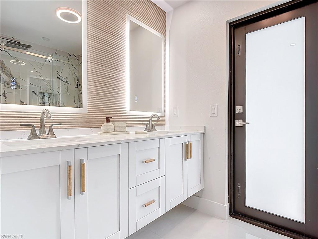 Bathroom featuring a marble finish shower and double vanity