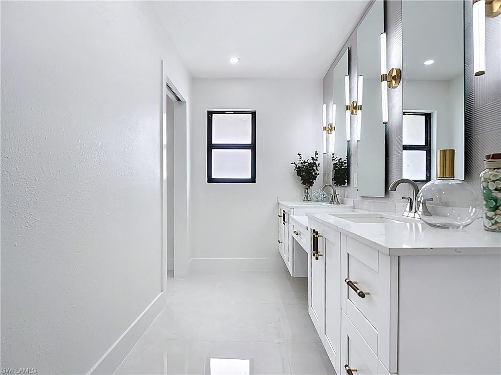 Bathroom featuring baseboards, double vanity, and tile patterned flooring