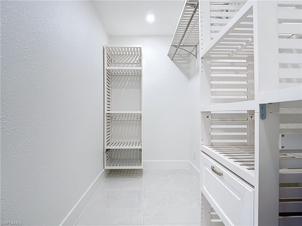 Spacious closet featuring light marble finish flooring