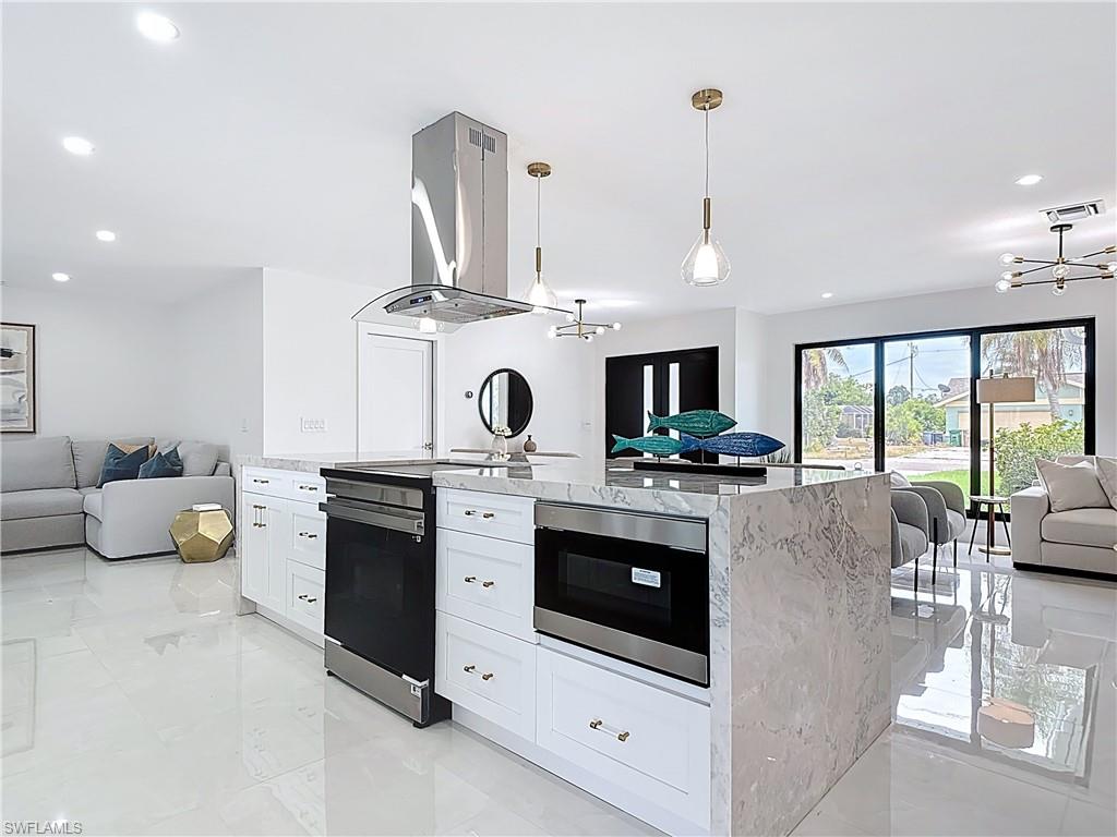 Kitchen featuring open floor plan, stainless steel range with electric cooktop, ventilation hood, a chandelier, and recessed lighting
