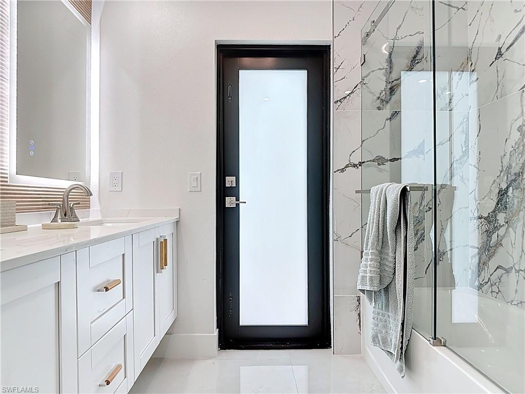 Full bath featuring shower / bath combination with glass door and vanity
