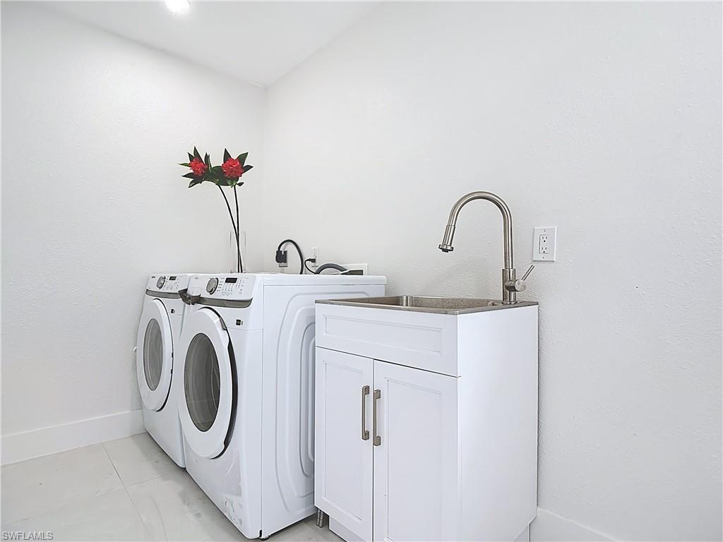 Laundry room featuring washer and clothes dryer, cabinet space, and baseboards