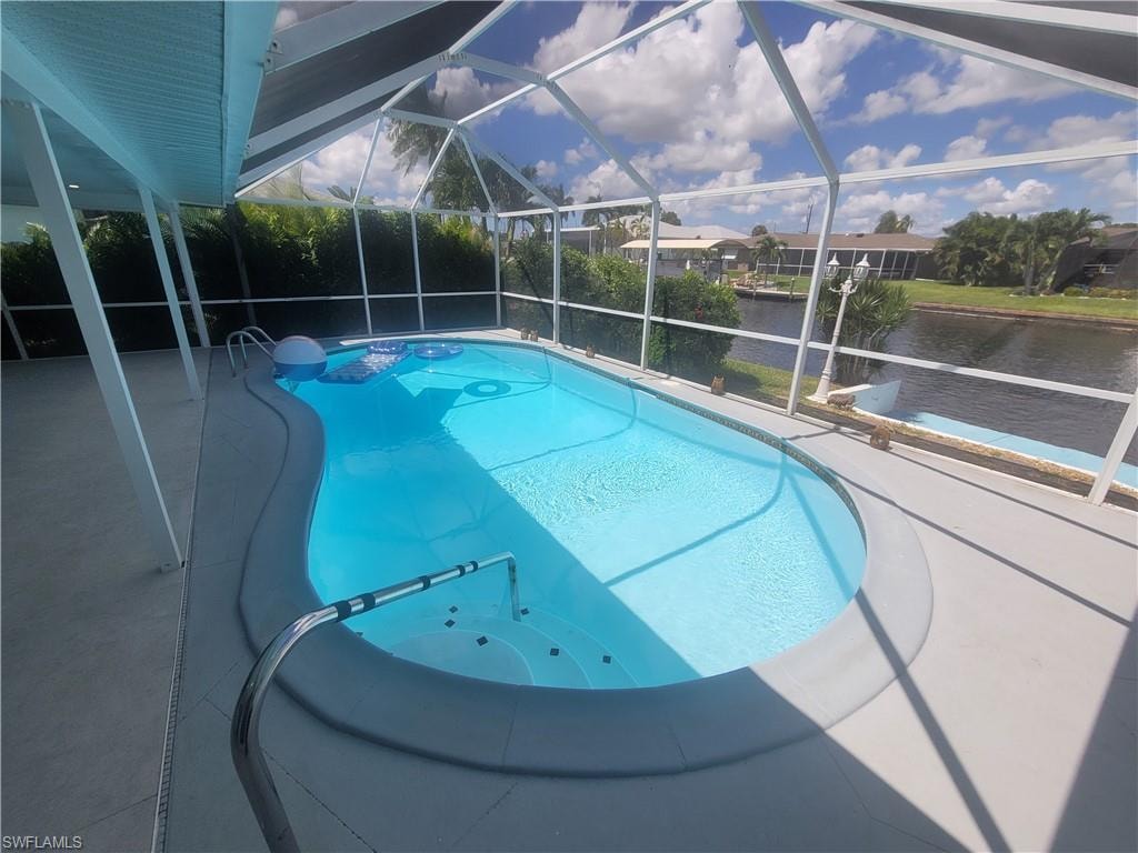 Swimming pool with a patio, glass enclosure, a water view, and a sunroom