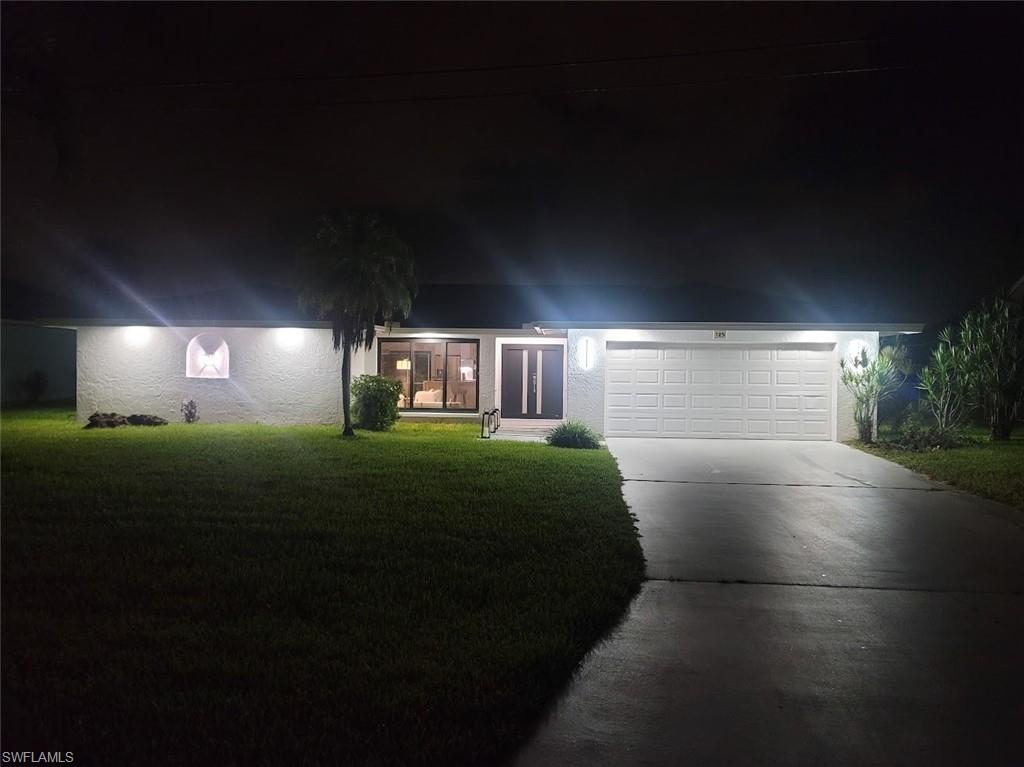 View of front of home with driveway, a lawn, and a garage