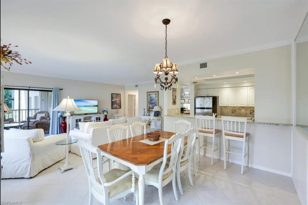 Dining space with a chandelier, crown molding, and light tile patterned floors