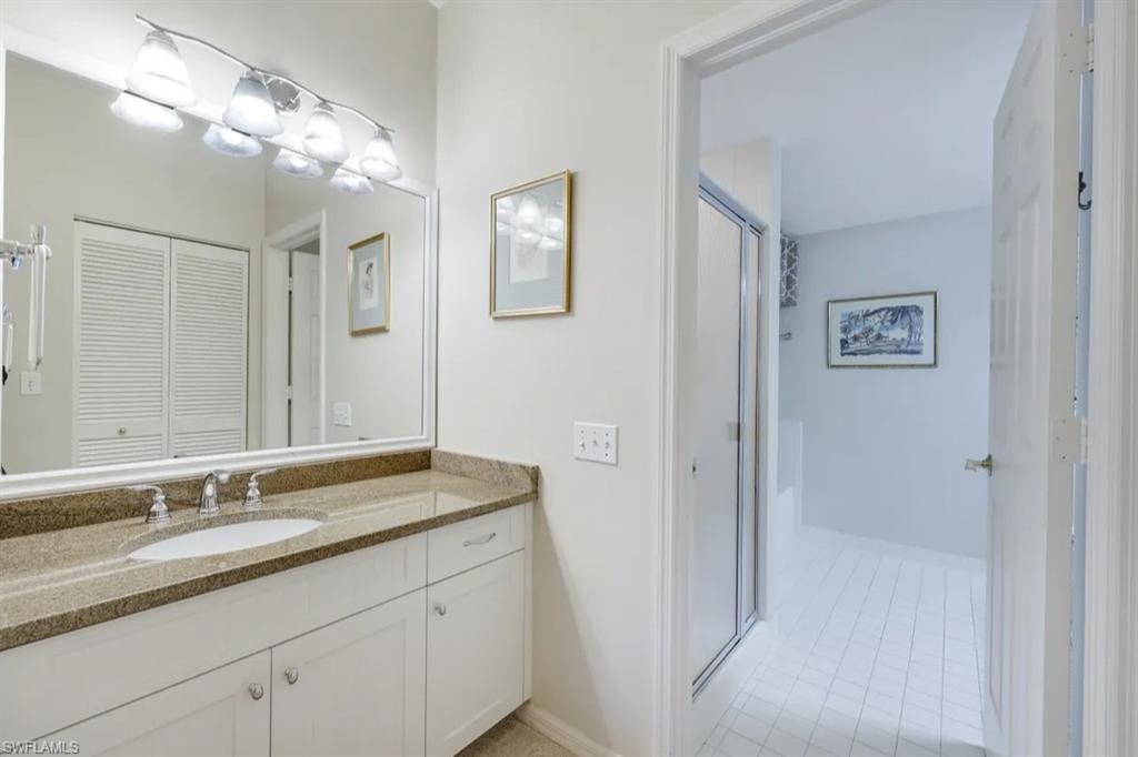 Bathroom featuring vanity, tile patterned floors, baseboards, a shower with shower door, and a closet