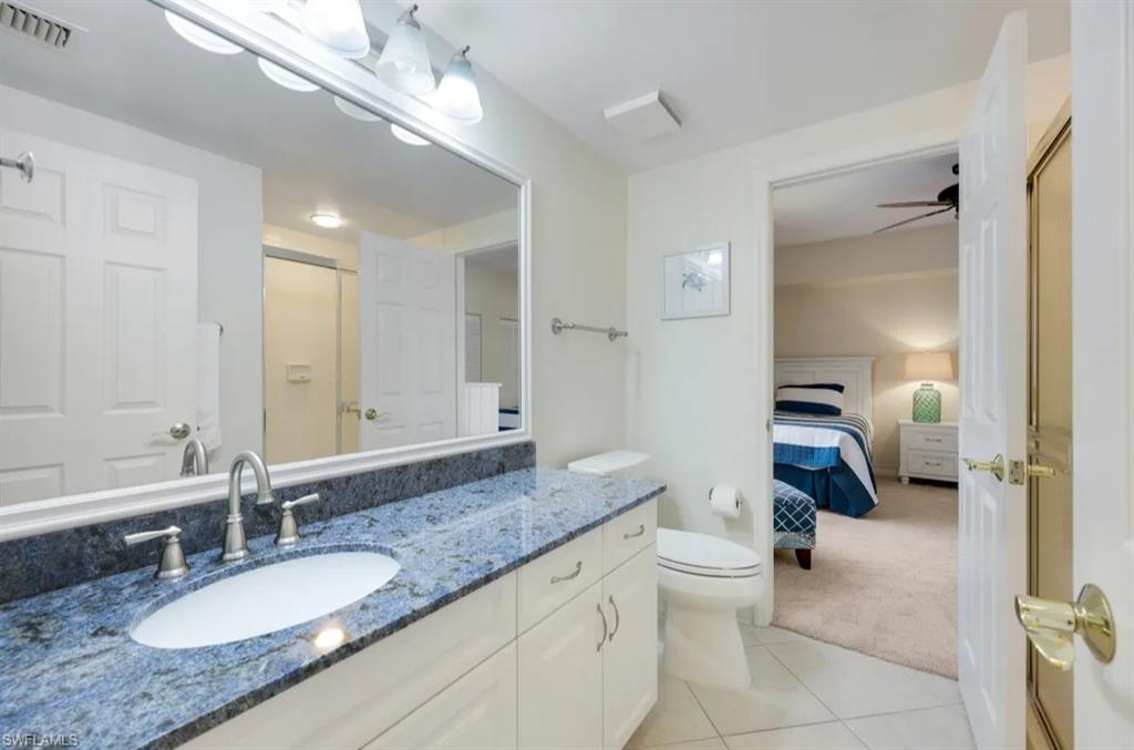 Ensuite bathroom with vanity, tile patterned flooring, toilet, and an enclosed shower