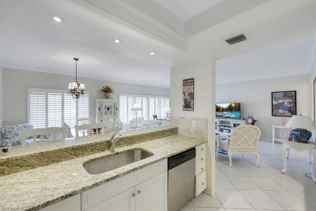 Kitchen with dishwasher, a sink, a chandelier, light stone counters, and recessed lighting