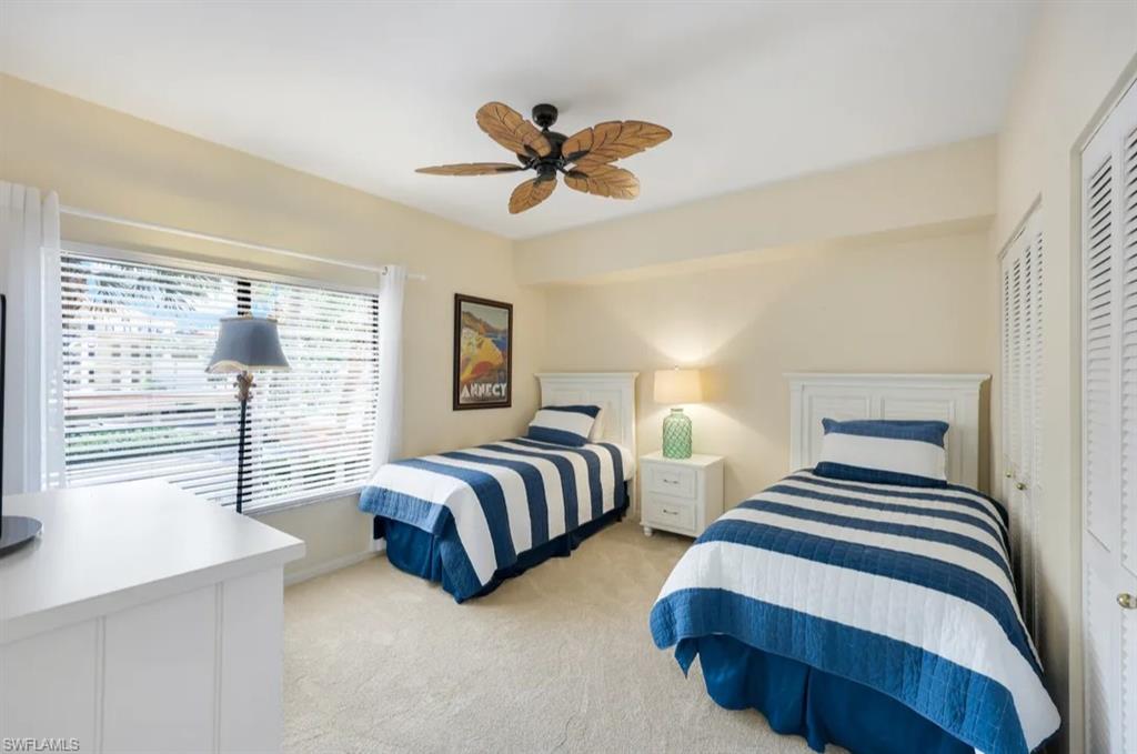 Bedroom featuring light carpet, a ceiling fan, and baseboards