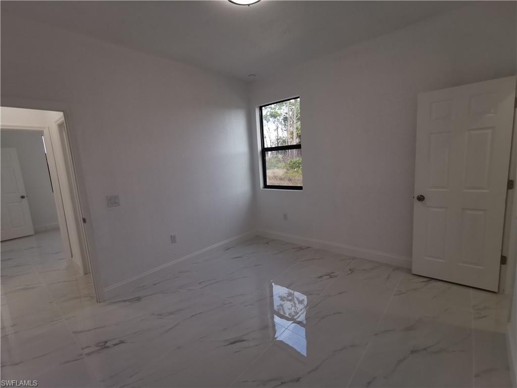 Empty room featuring baseboards and light marble finish floors