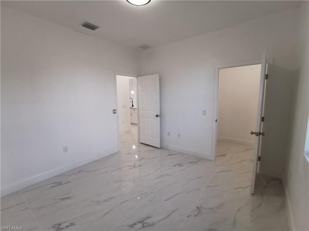 Unfurnished bedroom with baseboards and light marble finish flooring