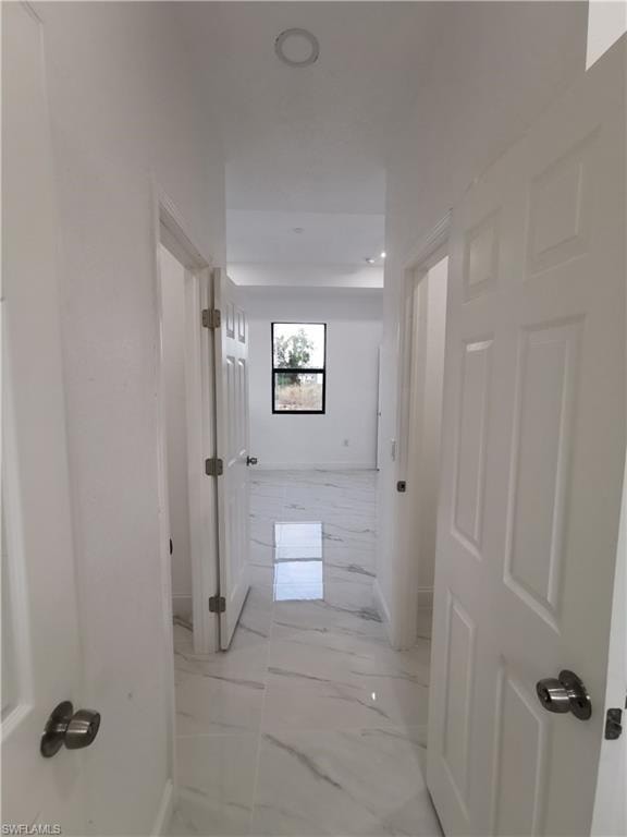 Hallway with light marble finish floors and baseboards