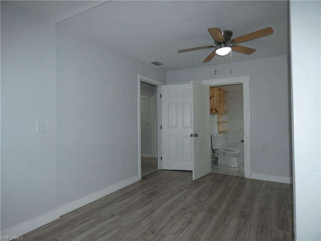 Empty room with wood finished floors, a ceiling fan, and baseboards