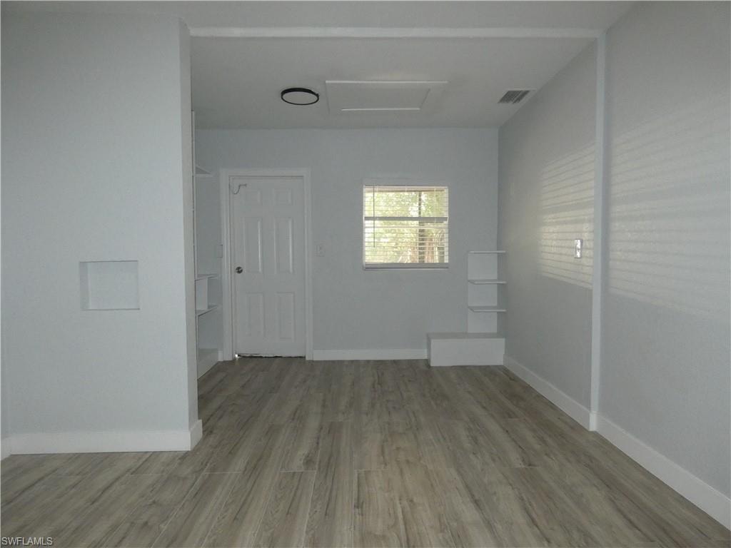 Spare room featuring wood finished floors, attic access, and baseboards