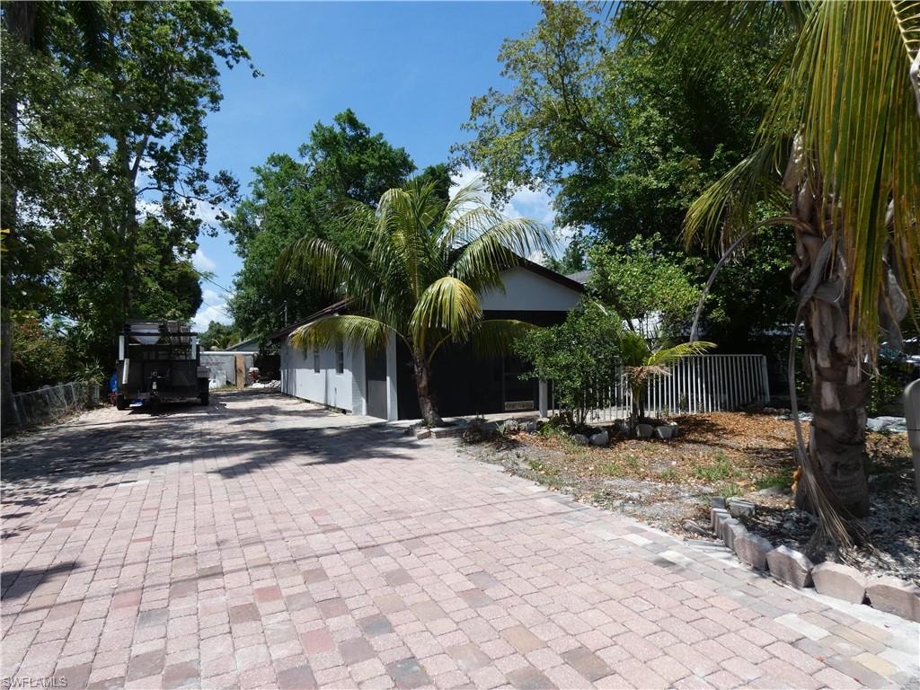 Obstructed view of property with fence and decorative driveway
