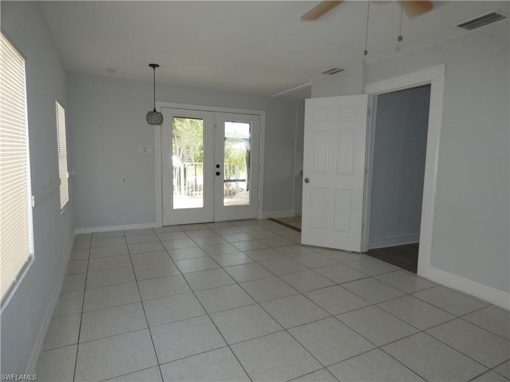 Empty room with ceiling fan, light tile patterned flooring, and baseboards