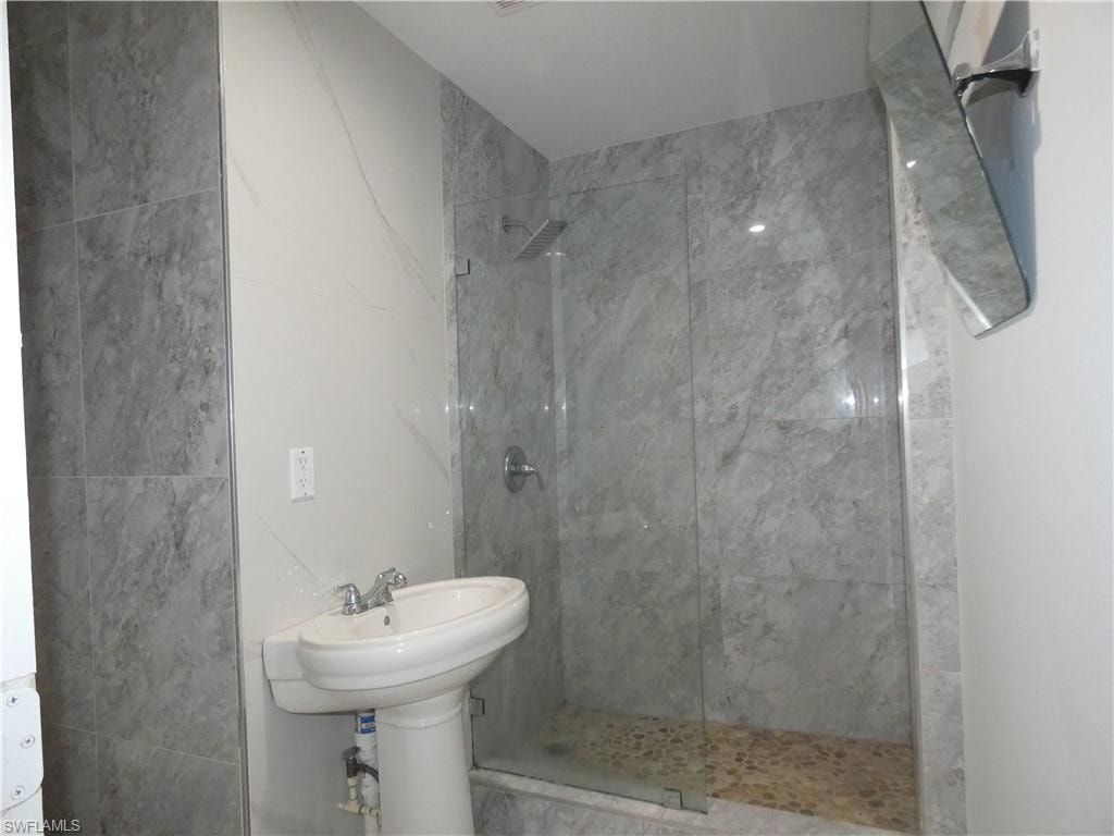 Full bathroom with tiled shower and tile walls