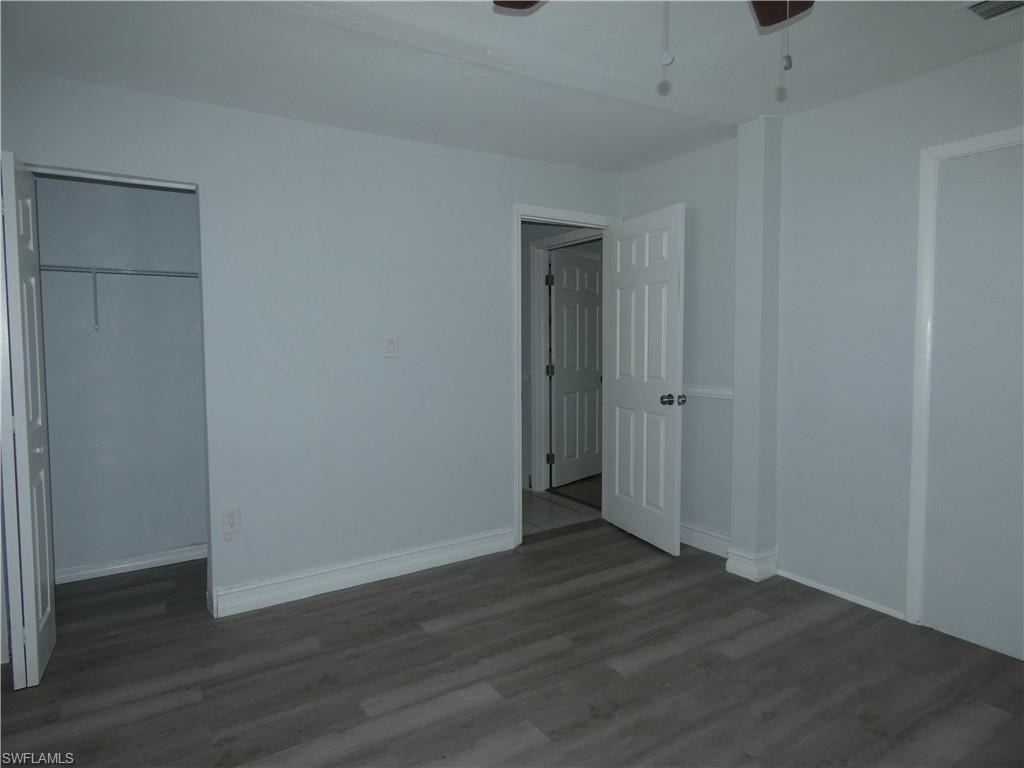 Unfurnished bedroom featuring wood finished floors, baseboards, and a closet
